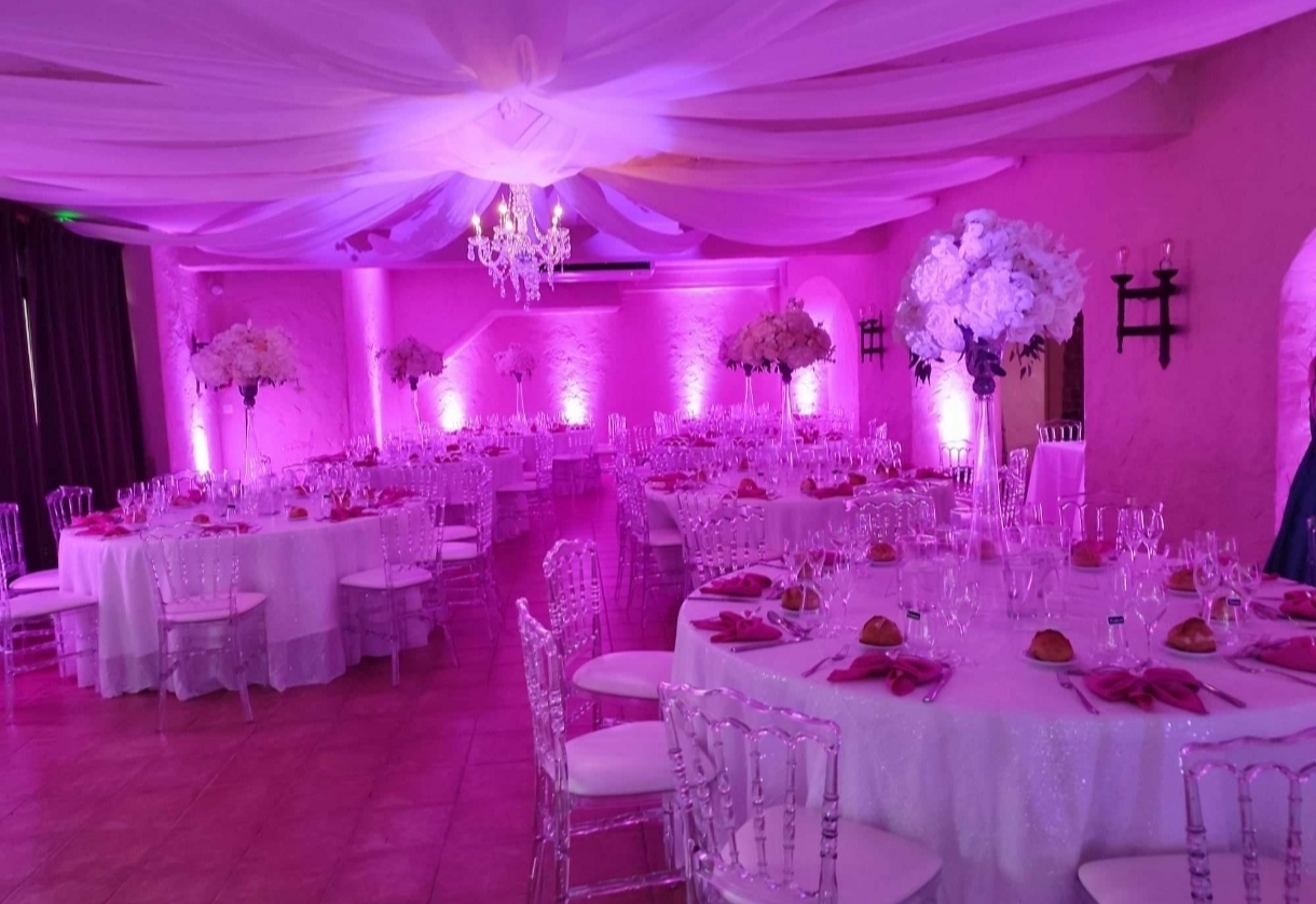 Salle de mariage chic illumin-event aux lumières rose-violette en occitanie, tables rondes élégantes et fleurs blanches